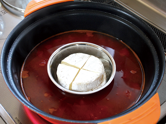 1.鍋に水、コンソメキューブ、トマト水煮缶を入れ、ひと煮立ちさせます。切り込みを入れ、レンジで1分程度温めたカマンベールチーズを、ココットやステンレス製の小さめの器に入れて、鍋の中心に。チーズが煮詰まって焦げ付かないよう、白ワインを加えて伸ばします。