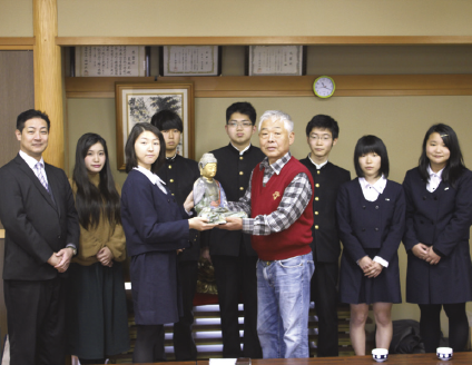 奉納には制作に関わった高校生や大学生が花坂地域を訪問。前区長の上田さん（右）に坐像を手渡さしました