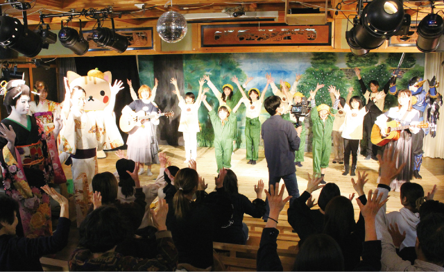 「すわん江戸村」での撮影風景。舞台上の人たちも観客席に座る人たちも元気いっぱいダンスを踊って3台のカメラで撮影