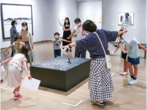 青木さん(手前右)が準備した鑑賞ツールを手に展示室を回る「こども美術館部」の様子