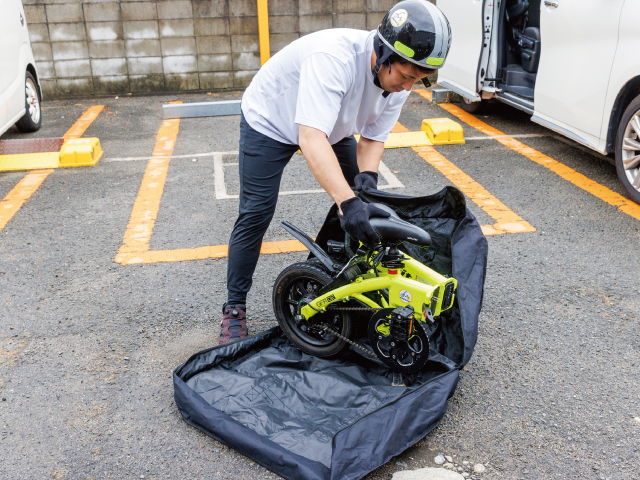 現場で電動バイクを畳んでバッグに収納